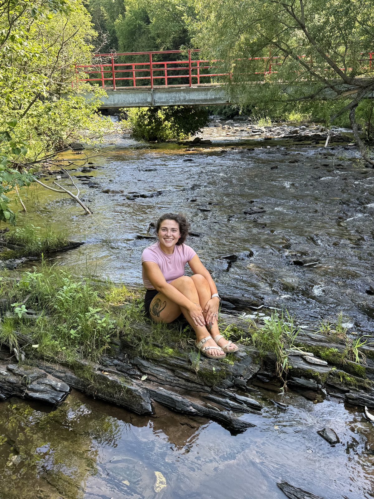 Lexy sitting by a creek outdoors